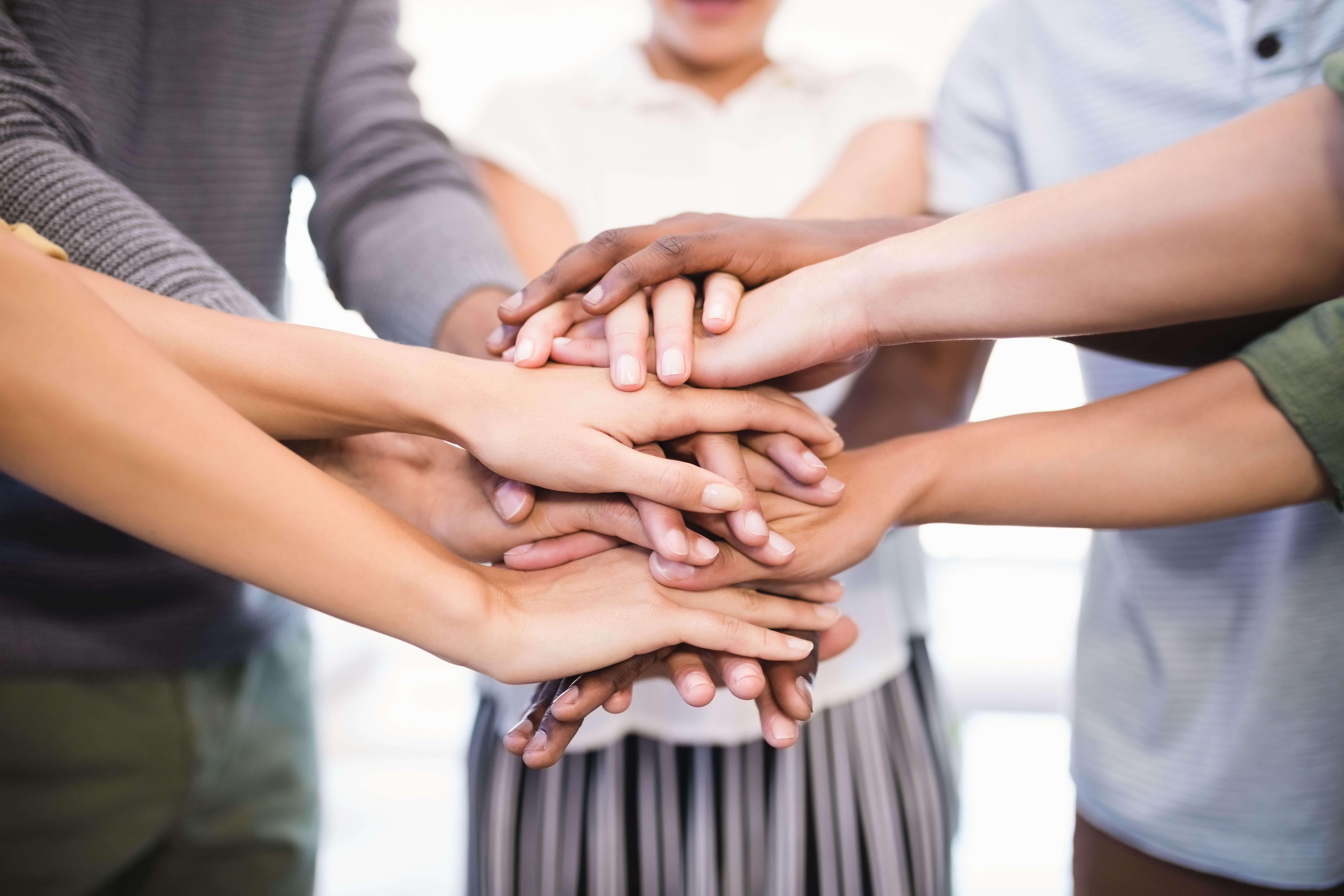 Group of five people putting their hands together - Reach a whole new audience with collaborative videos - Image