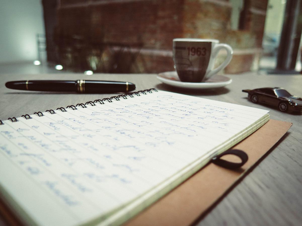 Cahier, un crayon et une tasse sur un bureau - Idées pour développer votre audience YouTube en tant qu'auteur-compositeur-interprète - Image