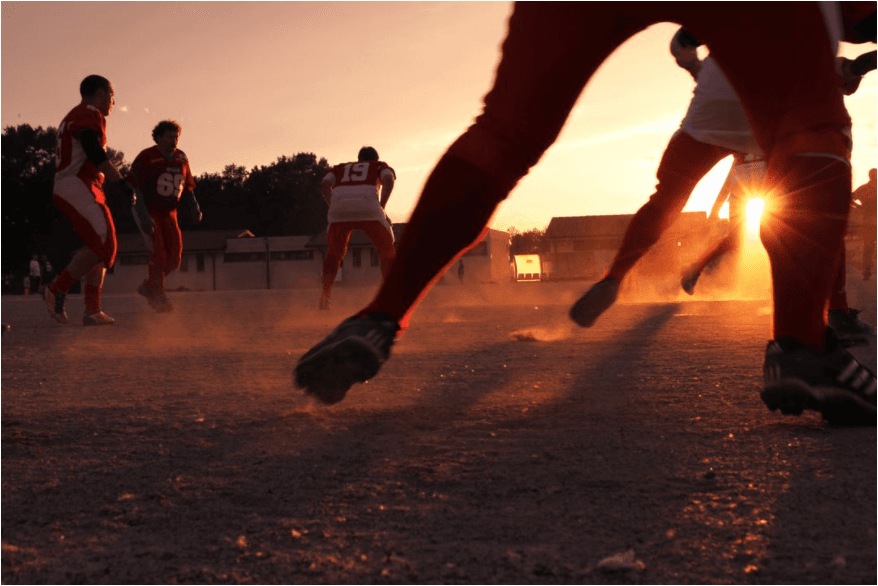 Equipo de fútbol jugando un partido al atardecer: cómo atraer fanáticos del deporte a tu canal cubriendo borradores y transferencias - Imagen