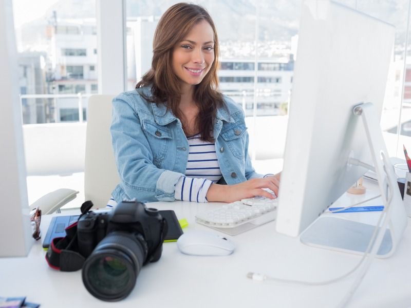 Femme souriante à un bureau avec caméra - 13 meilleurs conseils vidéo sur l&#39;immobilier - Image