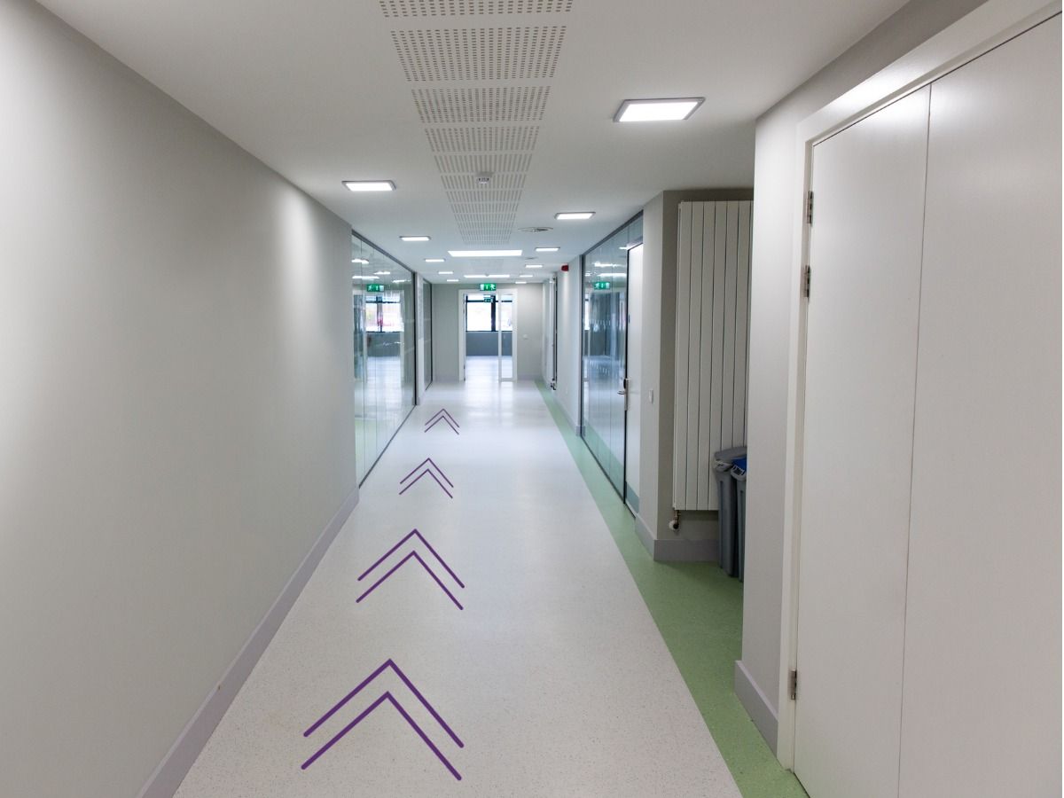 Vista de um corredor de um prédio de escritórios com setas no chão - O design como ferramenta para conectar efetivamente as pessoas com o meio ambiente - Imagem