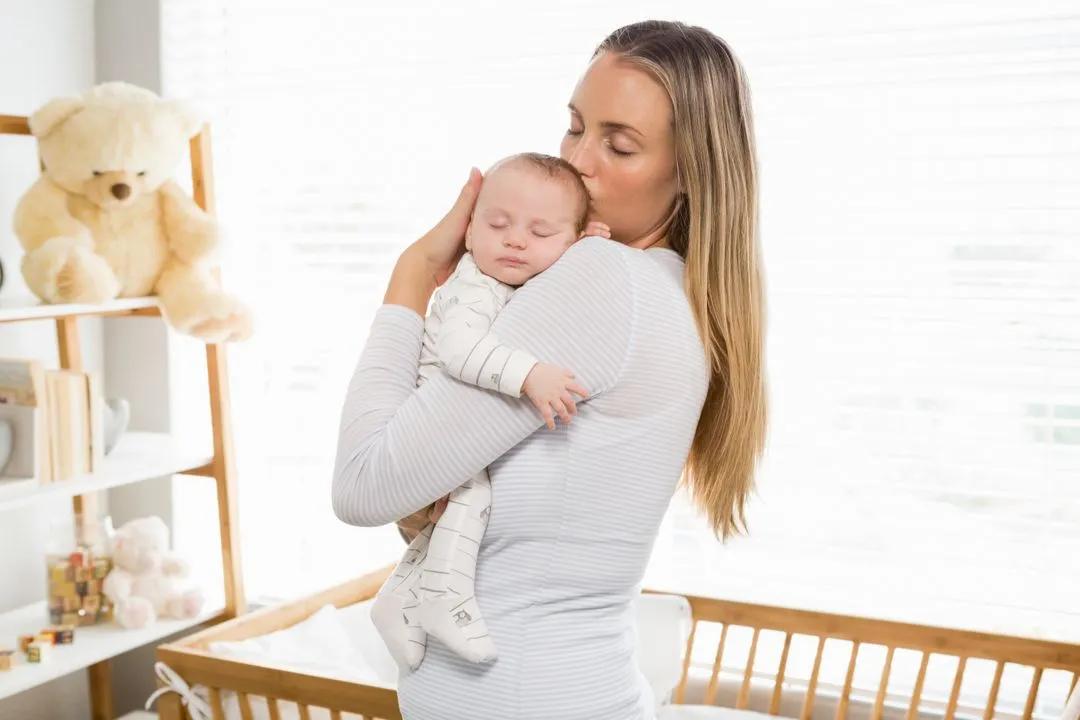 Mother holding and kissing her baby boy - Image