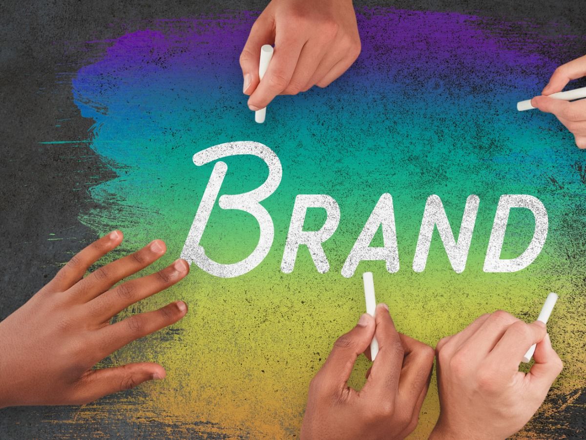 People write the word 'Brand' with white crayons on a rainbow background - Basics of brand awareness - Image