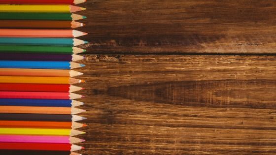 Wooden brown table with colouring pencils - How choosing the right palette for your brand can help you create an emotional connection with your audience - Image