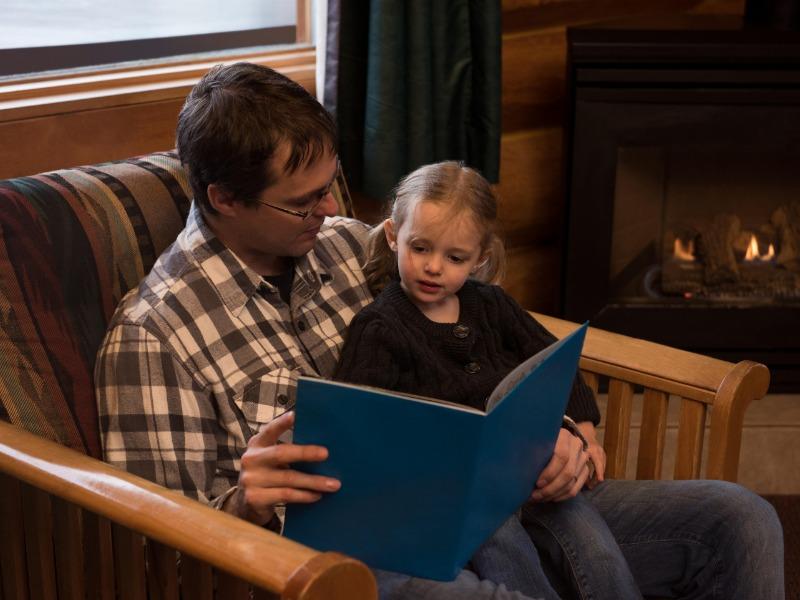 imagen de marketing creativa de un padre leyendo un libro para su hija