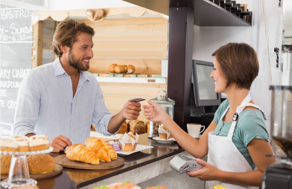 A customer at a bakery pays for a purchase with a credit card - Customer satisfaction is at the core of a successful loyalty program - Image