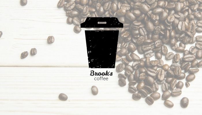 Ícone de caneca de café com texto Brook&#39;s coffee em um fundo de grãos de café derramados sobre uma mesa de madeira