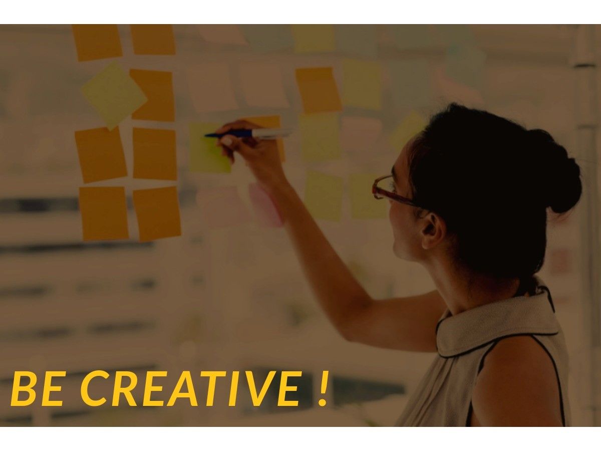 Woman writing on a sticky note on a glass wall for brainstorming - The best marketing strategies and techniques for small businesses in 2023 - Image