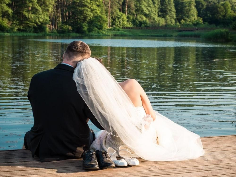 Wife and groom sitting on a pier by the lake - 70 creative ways to boost employee morale - Image