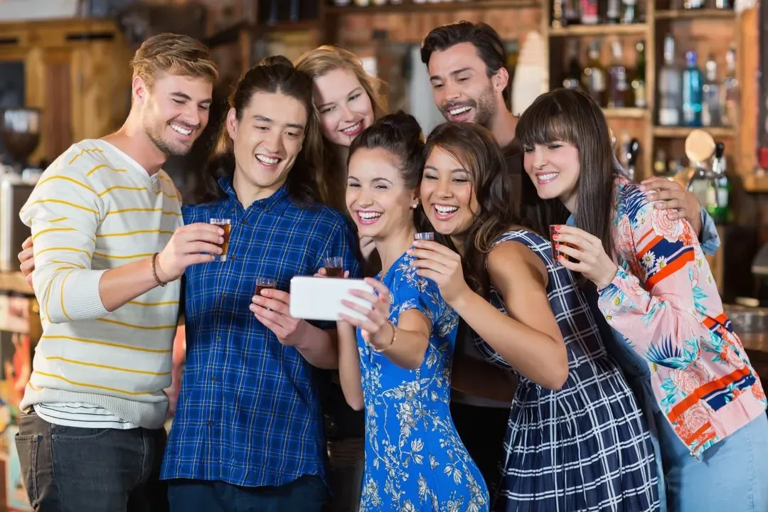 Cheerful friends taking selfie while holding short glasses - Image