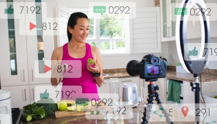 Microinfluenciador na frente da câmera na cozinha sobreposto com contagens transparentes de curtir, enviar mensagens e reproduzir vídeos