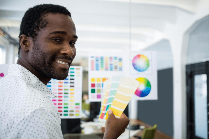 Black male graphic designer holding a color swatch - Choosing the right color palette for your vision board - Image