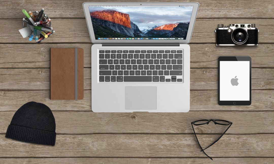 Laptop, Kamera, Notebook und ein Tablet auf einem Schreibtisch