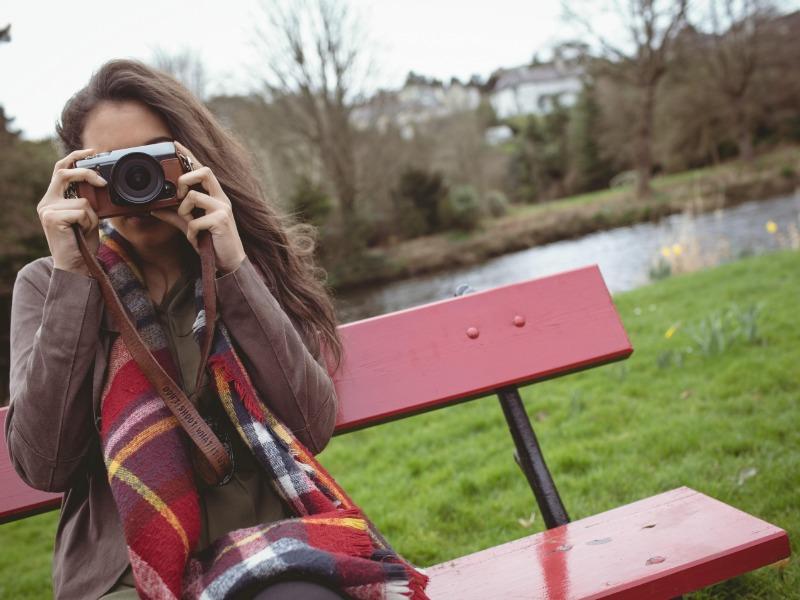 Vlogger sur banc rouge avec rivière derrière - Comment créer un vlog - Image