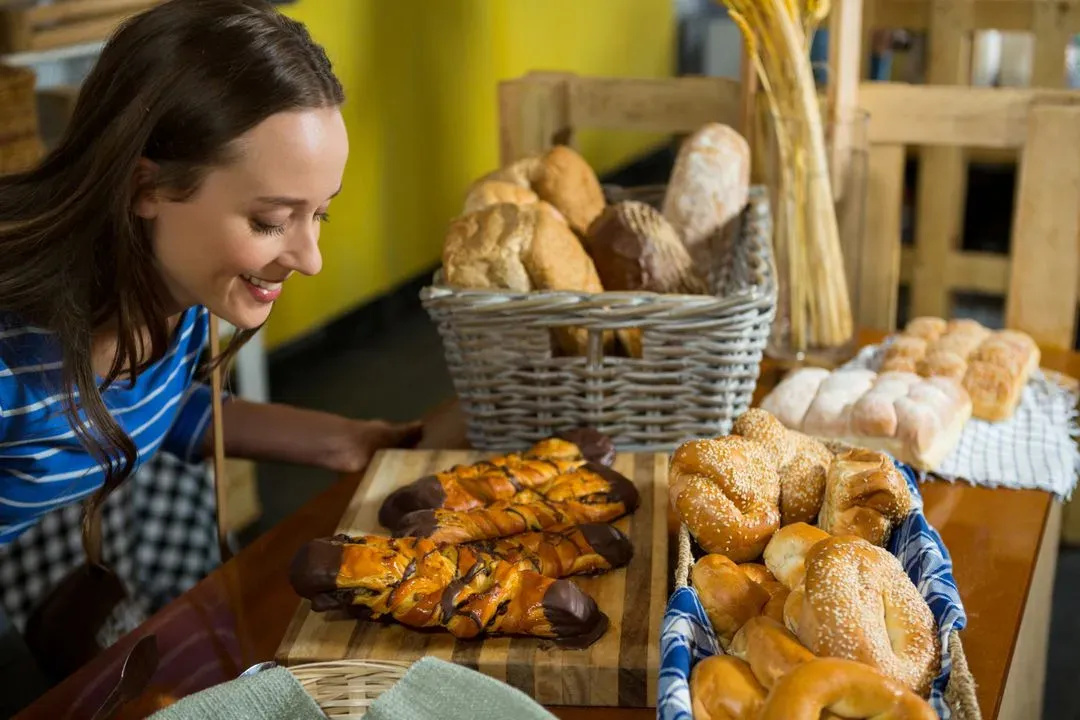 Smiling woman smelling a bakery snacks at counter - Image
