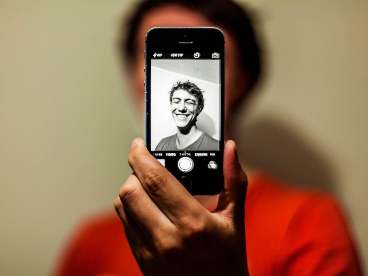 Pessoa segurando smartphone na frente do rosto para tirar selfie