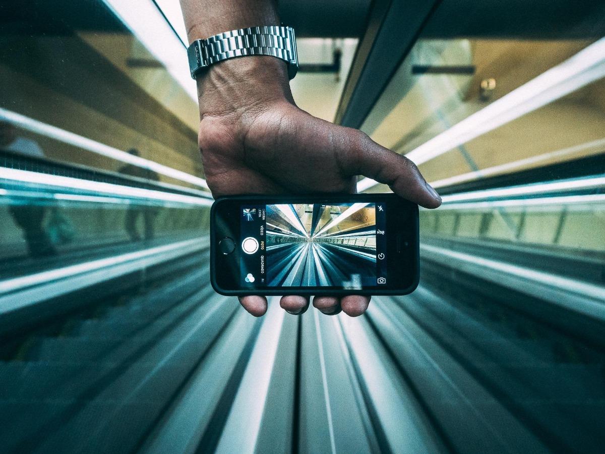 Main tenant l&#39;appareil photo du smartphone pour filmer l&#39;escalator