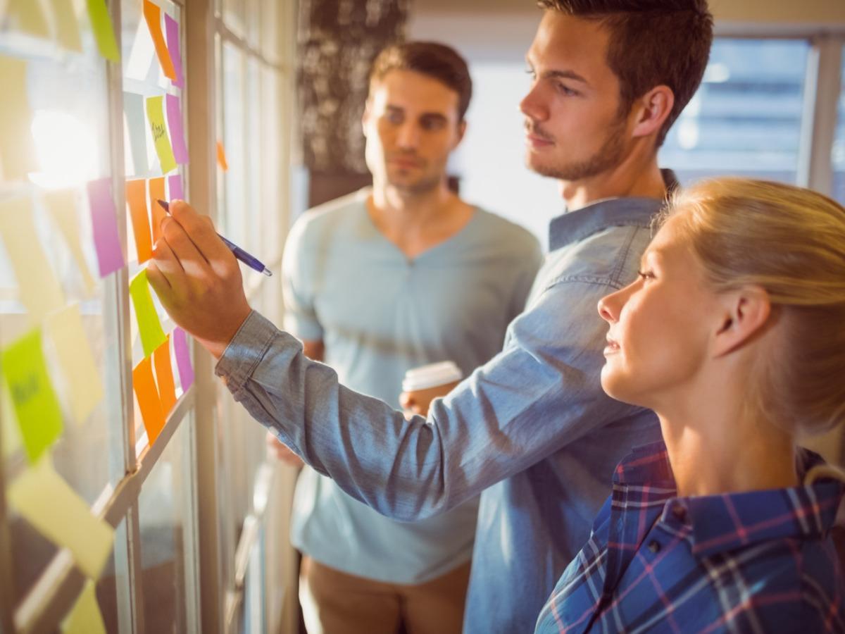 Image of co-workers writing on sticky notes on windows - Tips for creating a social media content calendar: Key factors to consider - Image