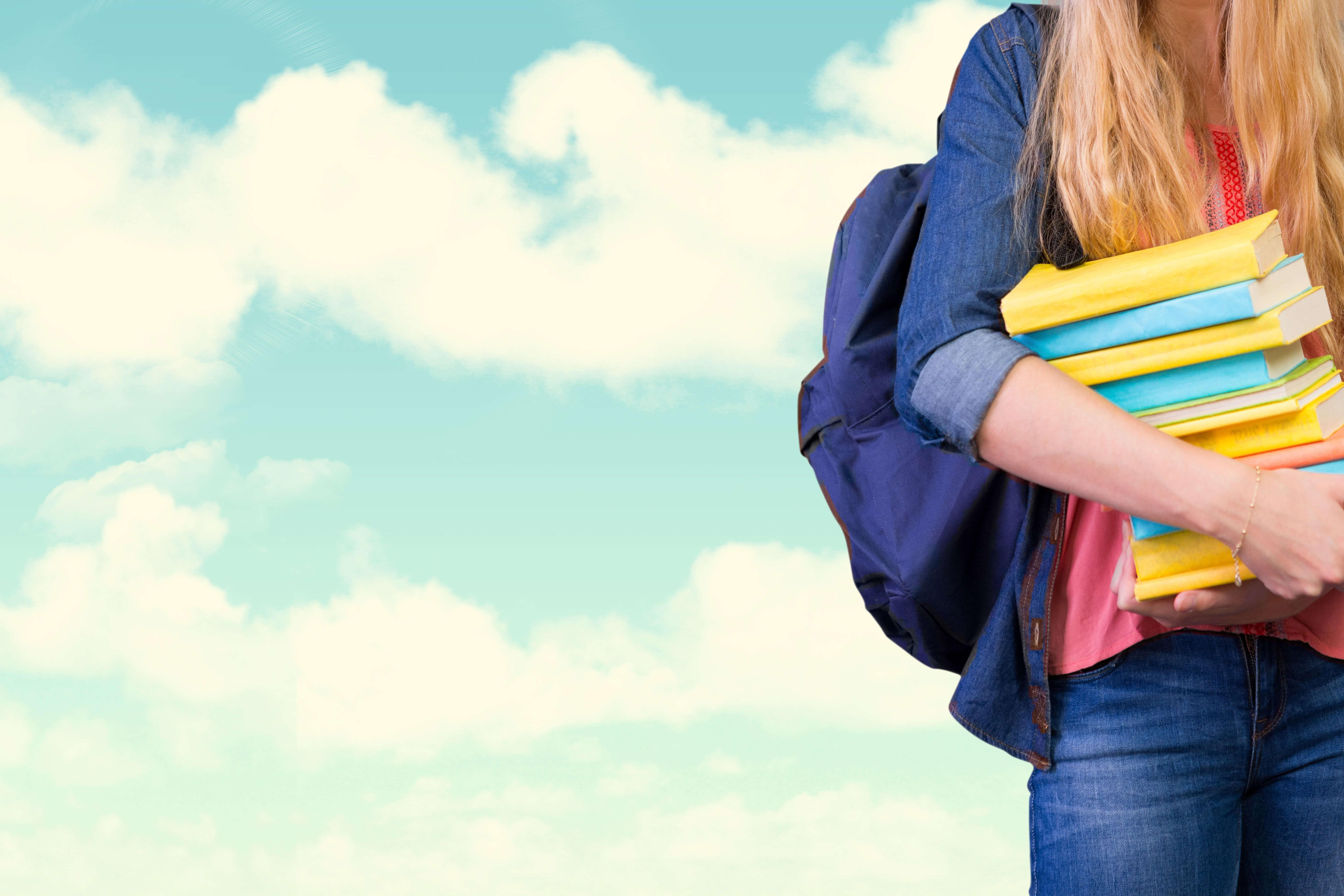 Estudiante de pie sosteniendo libros con fondo de cielo