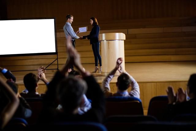 Two people shake hands on stage - The 100 best event marketing ideas of 2019 - Image