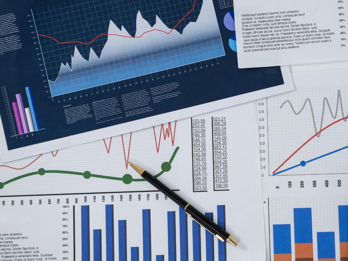 An image of documents with various graphs and a pen lying on top of them - The ultimate brand audit guide - Image