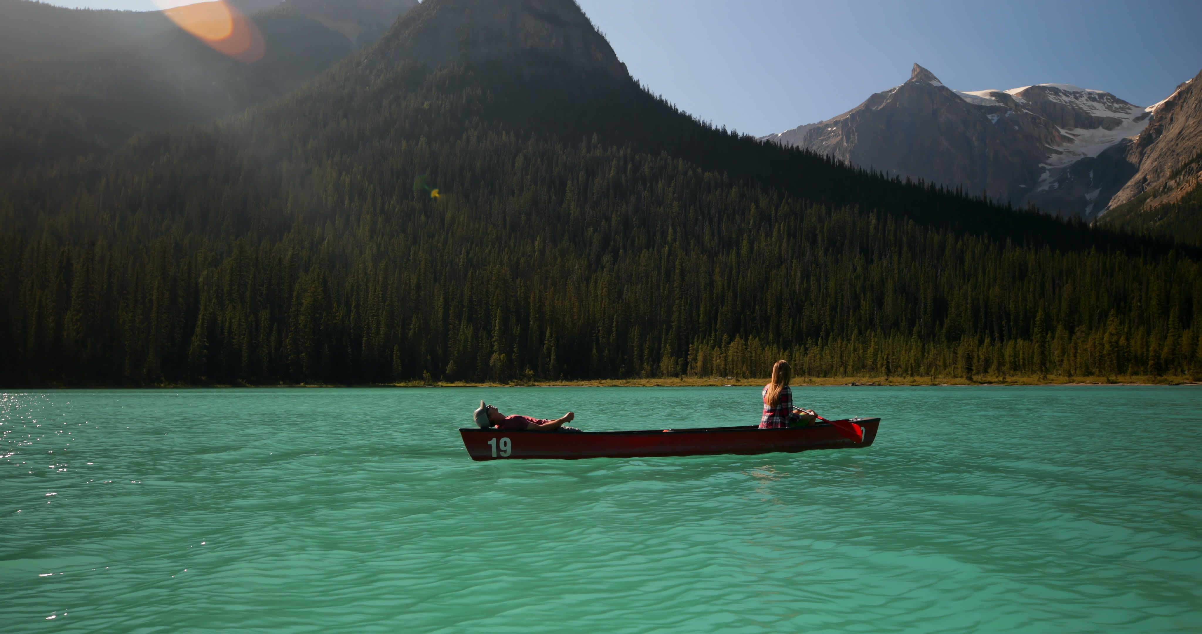 Paar beim Kanufahren auf einem türkisfarbenen See mit Bergblick - Bild