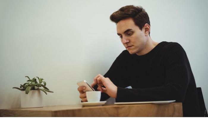 homme regardant le téléphone au café - marketing relationnel pour une entreprise prospère - Image