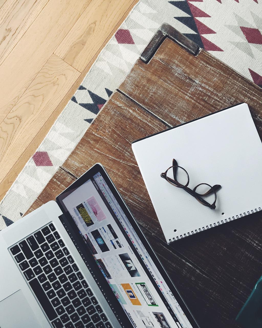 Top image of a desk with a notepad, laptop and glasses lying on it - How to start a part-time business that works - Image