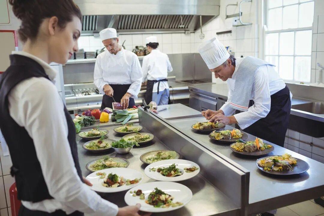 Waitress taking food dishes from order station - Image