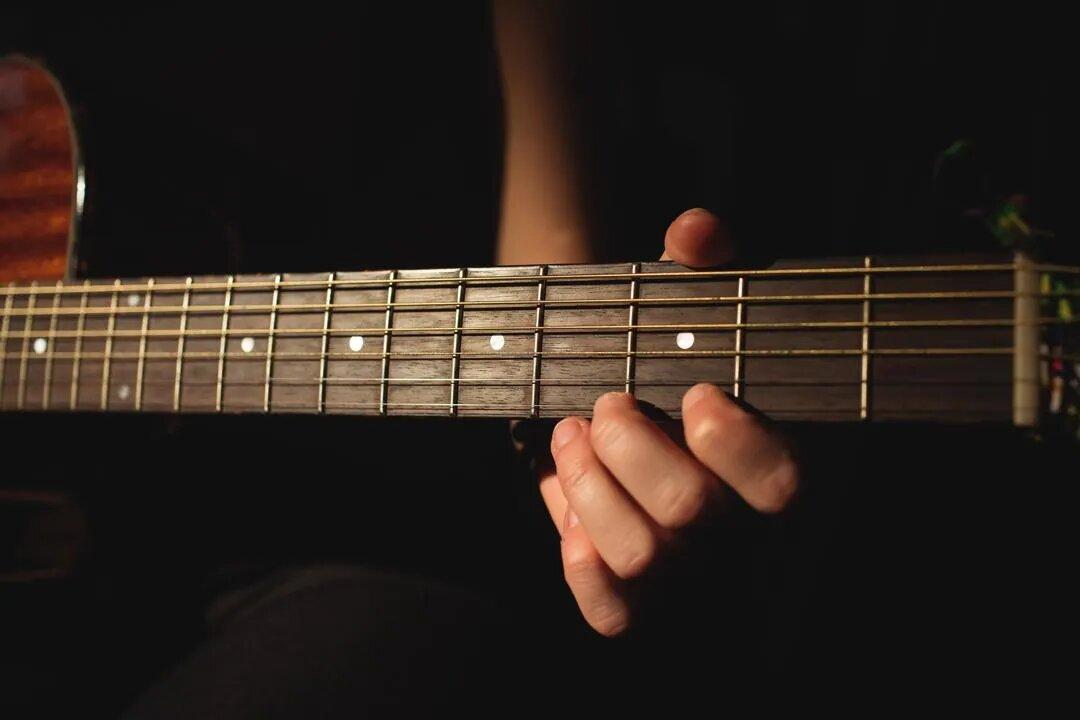 Woman playing a guitar in music school - Image