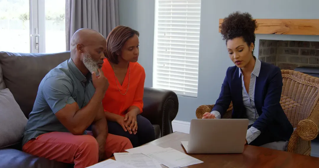 Mixed race female real estate agent discussing over property with mature couple on laptop at home - Image