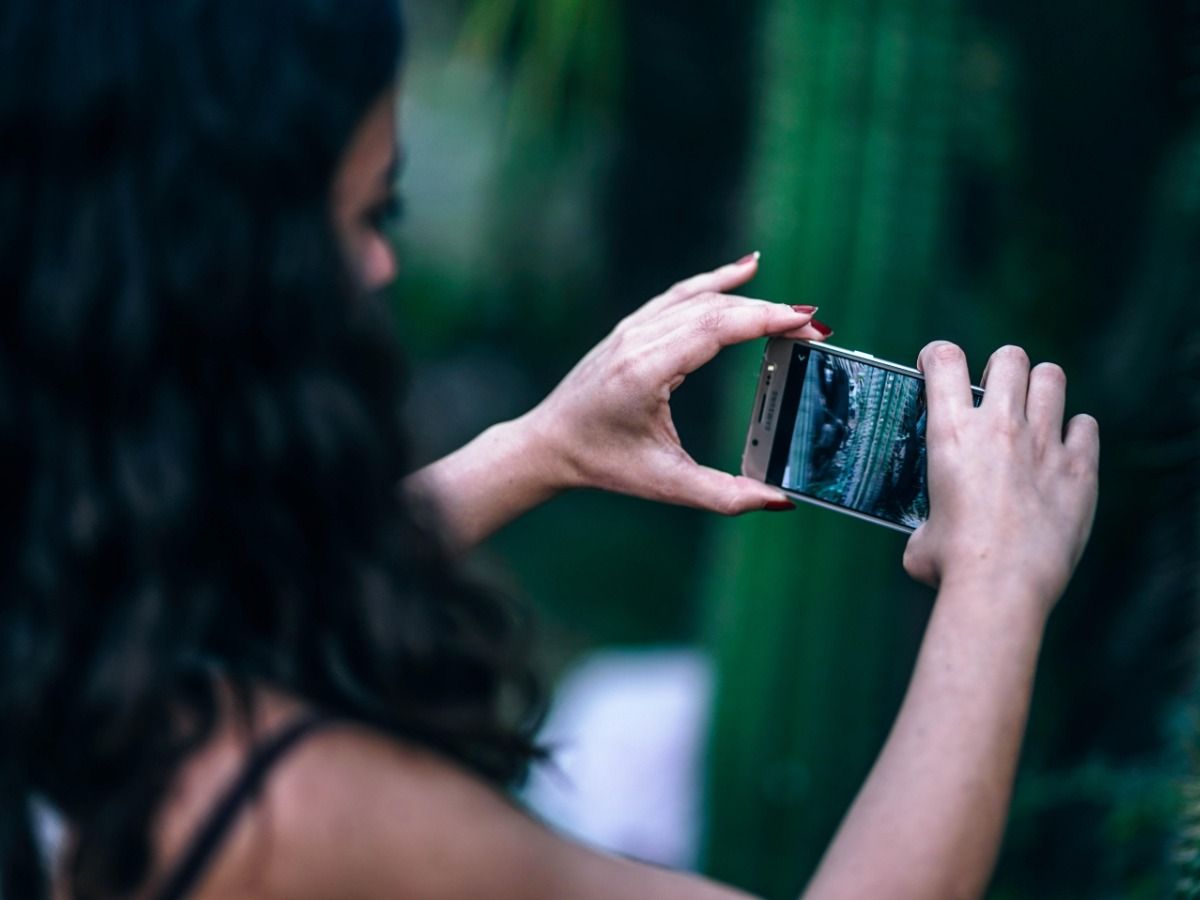 A young woman takes pictures on her smartphone - Essential video marketing tips for beginners in 2021 - Image