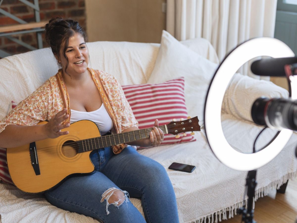 A young woman filming herself playing the guitar - Essential video marketing tips for beginners in 2021 - Image