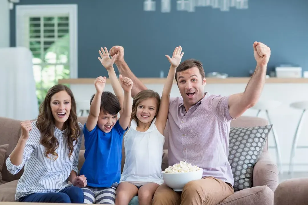 Family cheering while watching tv in living room at home - Image