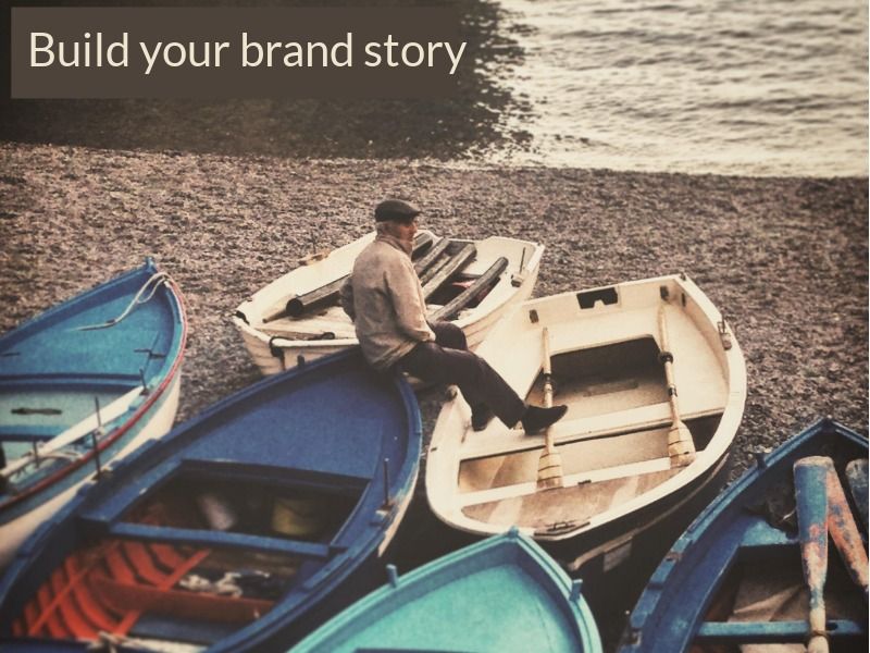 homem sentado na proa de um barco em uma praia com texto constrói a história da nossa marca